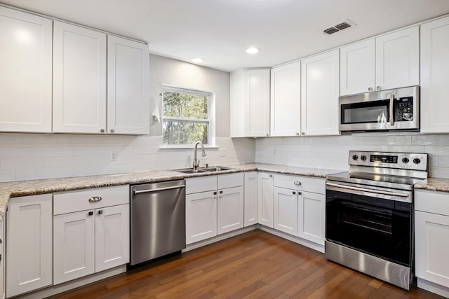 kitchen featuring appliances with stainless steel finishes, white cabinetry, a sink, and visible vents