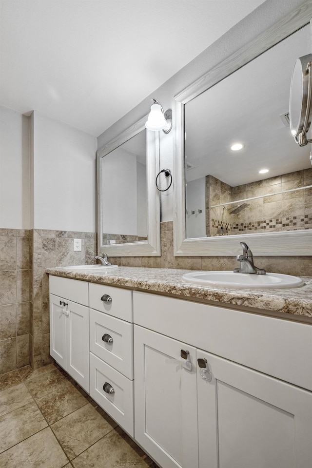 full bath with wainscoting, a sink, tile walls, and double vanity