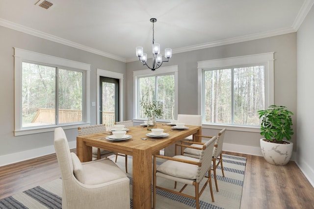 dining space featuring a healthy amount of sunlight, ornamental molding, and hardwood / wood-style floors