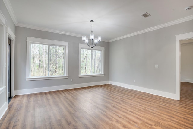 spare room featuring hardwood / wood-style flooring, an inviting chandelier, and crown molding