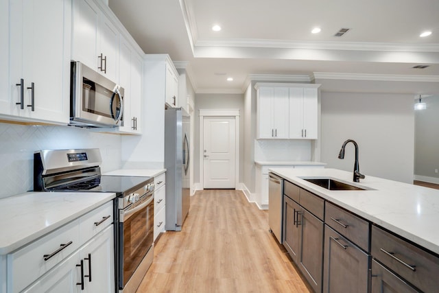 kitchen with sink, stainless steel appliances, white cabinetry, and crown molding