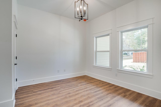 empty room featuring hardwood / wood-style flooring and a chandelier