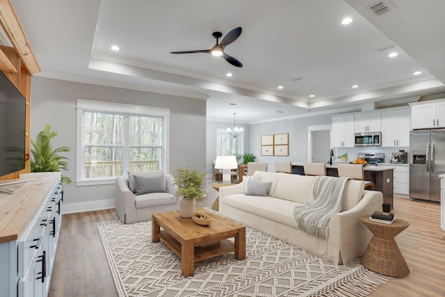 living room with ornamental molding, light hardwood / wood-style flooring, and a tray ceiling