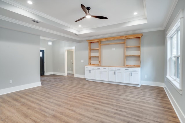 unfurnished living room featuring crown molding, light wood-type flooring, ceiling fan, and a raised ceiling