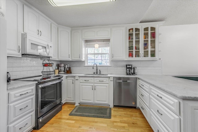 kitchen featuring light wood-type flooring, white cabinetry, stainless steel appliances, and a sink