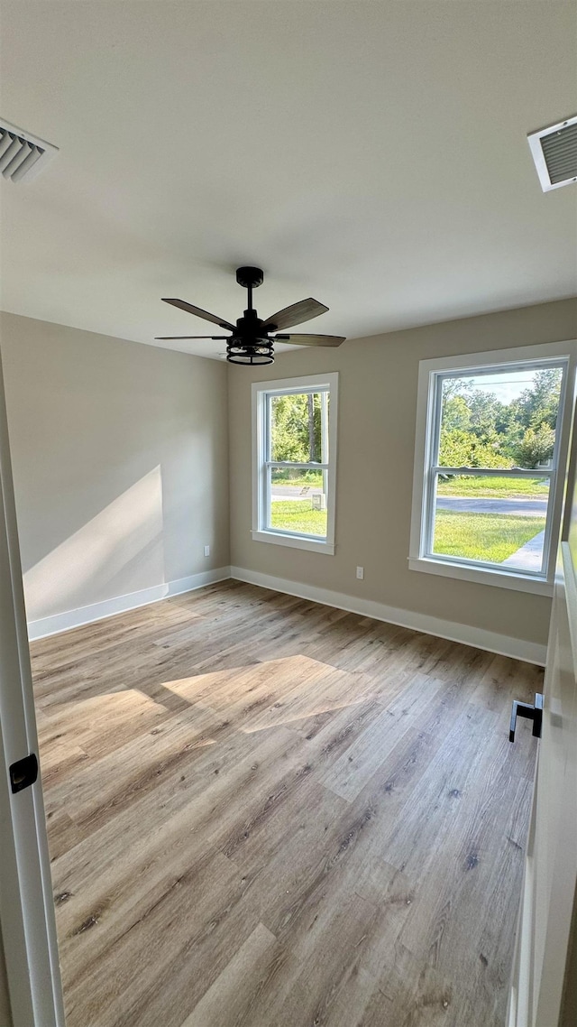 spare room featuring plenty of natural light, wood finished floors, and ceiling fan
