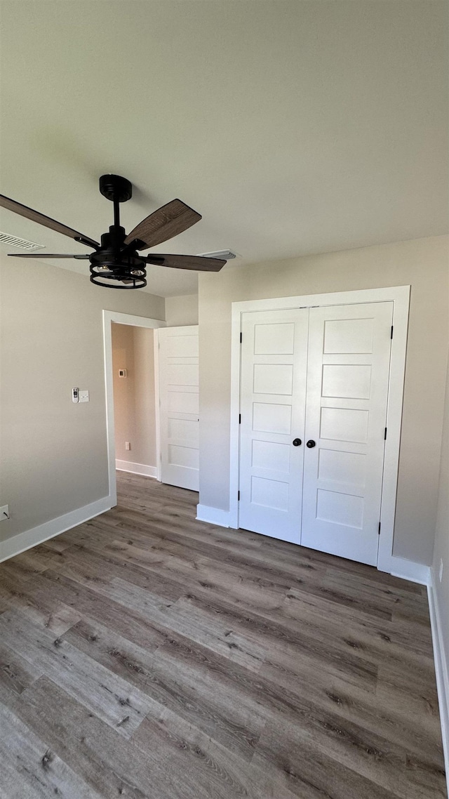 unfurnished bedroom with wood finished floors, a closet, and a ceiling fan