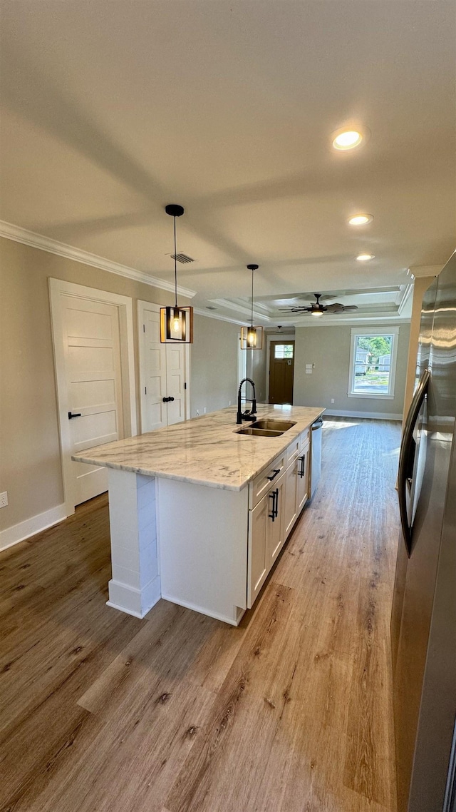 kitchen featuring stainless steel appliances, crown molding, a center island with sink, white cabinets, and wood finished floors