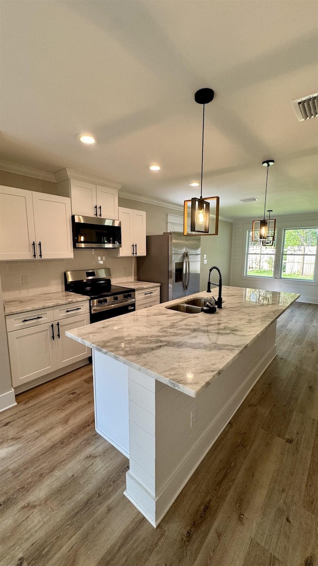 kitchen featuring stainless steel appliances, ornamental molding, white cabinetry, light wood-type flooring, and recessed lighting