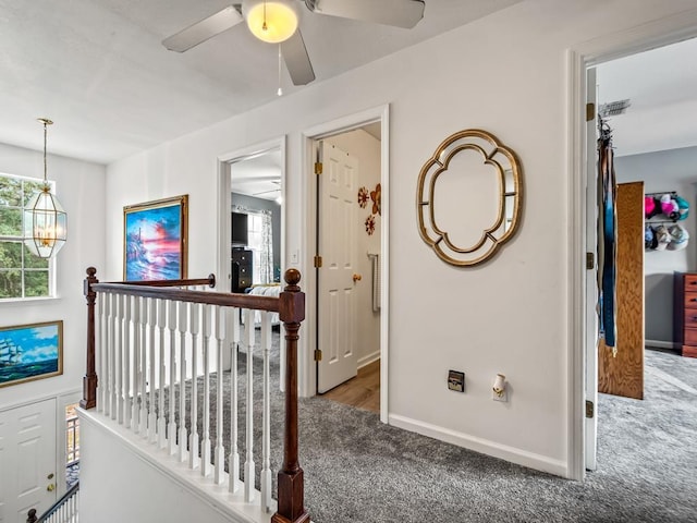 hall featuring a chandelier and dark carpet