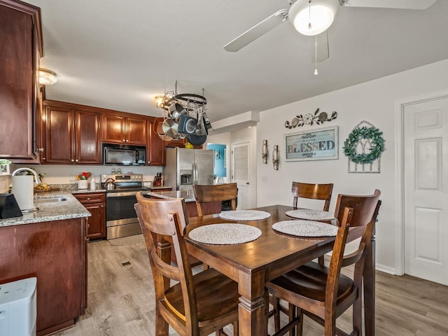 dining space with ceiling fan, sink, and light wood-type flooring