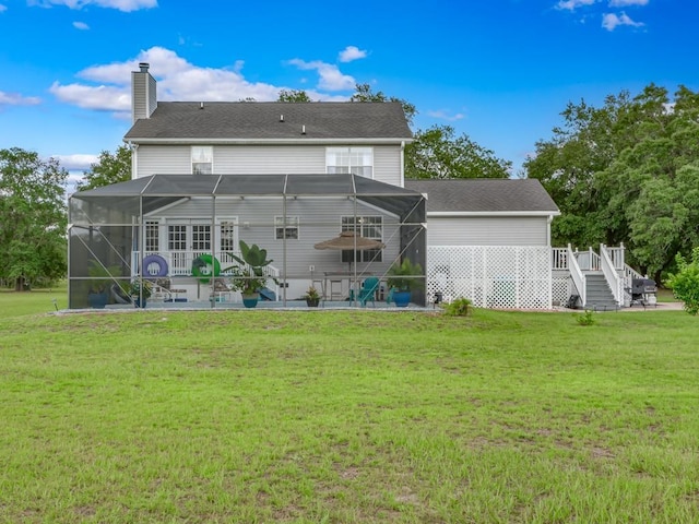 rear view of house featuring a wooden deck, a patio area, glass enclosure, and a lawn