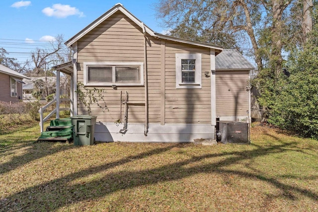 rear view of property featuring metal roof, a lawn, and cooling unit