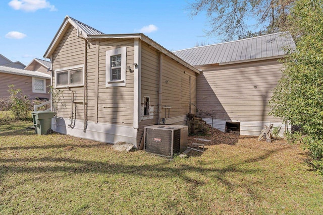 rear view of property featuring metal roof, a yard, and cooling unit