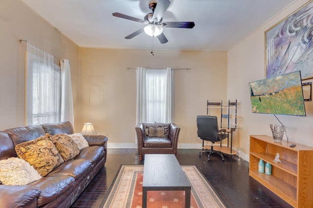 living area with a healthy amount of sunlight, baseboards, dark wood finished floors, and a ceiling fan