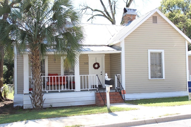 view of front of property with metal roof and a chimney