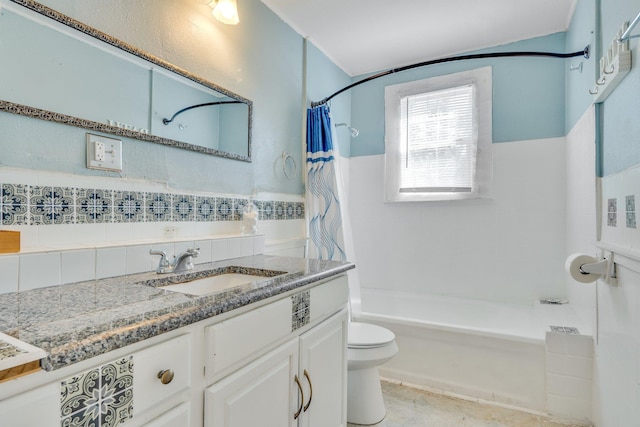 bathroom with a wainscoted wall, tile walls, toilet, shower / bath combo, and vanity