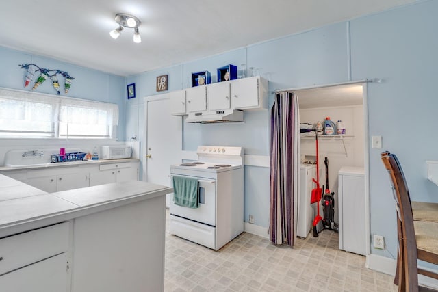 kitchen with white appliances, white cabinets, washing machine and clothes dryer, light countertops, and under cabinet range hood