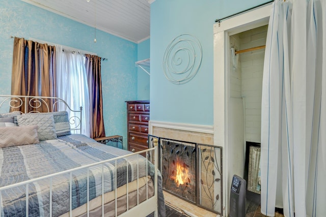 bedroom with a warm lit fireplace and crown molding