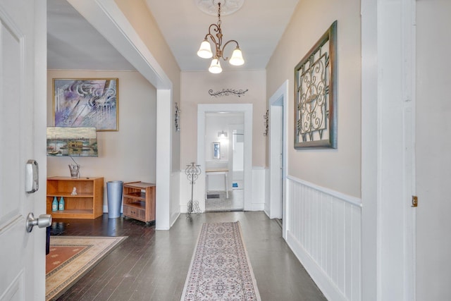 entryway with a chandelier, dark wood-style flooring, and wainscoting