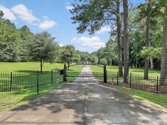 view of gate with fence and a yard