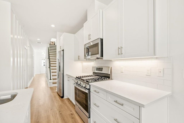 8372 Bull Headley Rd, Tallahassee, FL 32312 - kitchen with stainless steel appliances, light wood-style floors, tasteful backsplash, white cabinetry, and recessed lighting