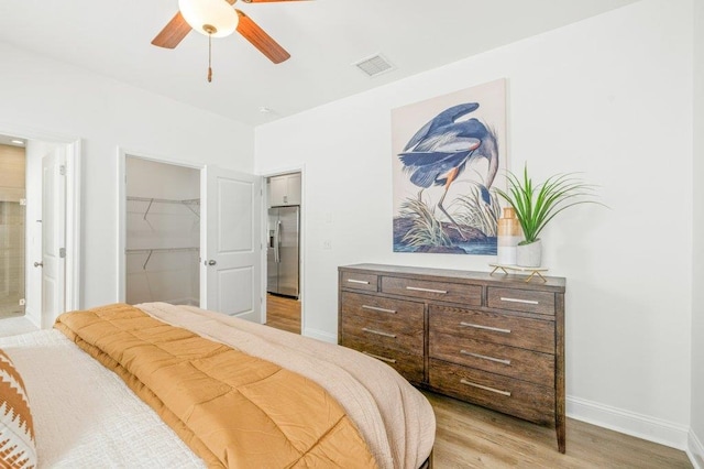 8372 Bull Headley Rd, Tallahassee, FL 32312 - bedroom featuring stainless steel refrigerator with ice dispenser, light wood-type flooring, a spacious closet, baseboards, and ensuite bathroom