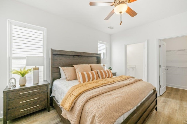 8372 Bull Headley Rd, Tallahassee, FL 32312 - bedroom featuring light wood-style floors, connected bathroom, a walk in closet, and a ceiling fan