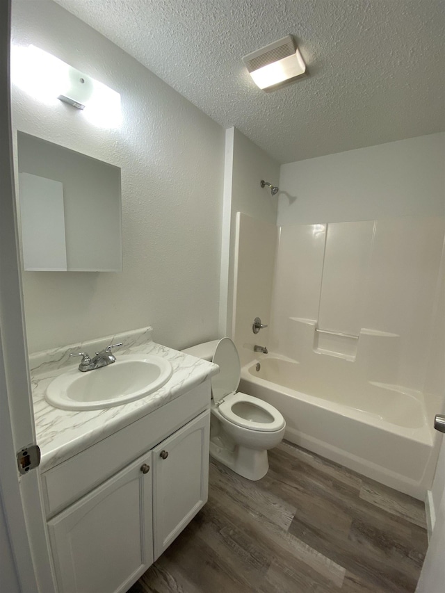4350 Fortner Cir, Perry, FL 32347 - bathroom with a textured ceiling, wood finished floors, vanity, and tub / shower combination