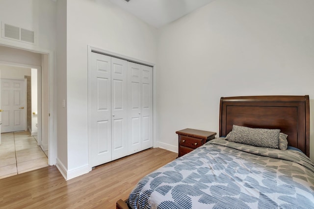 bedroom featuring a high ceiling, a closet, and light hardwood / wood-style flooring