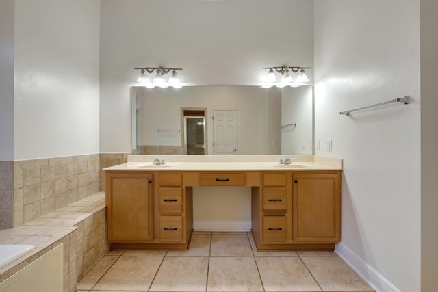 bathroom with vanity, tile patterned flooring, and tiled tub