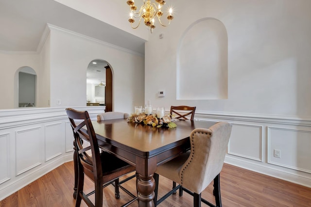 dining room with ornamental molding, light hardwood / wood-style flooring, and an inviting chandelier