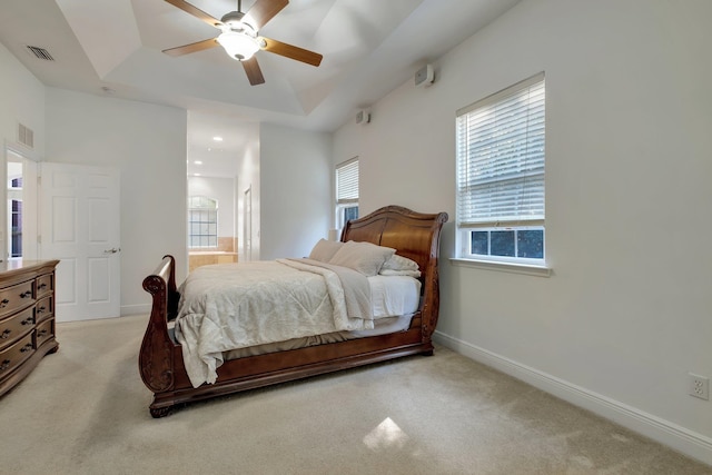 bedroom with light colored carpet, ceiling fan, and a raised ceiling