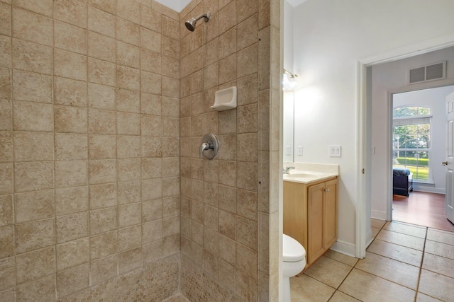 bathroom featuring tile patterned floors, vanity, toilet, and a tile shower