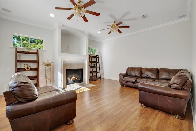 living room featuring a fireplace, ceiling fan, light hardwood / wood-style flooring, and ornamental molding