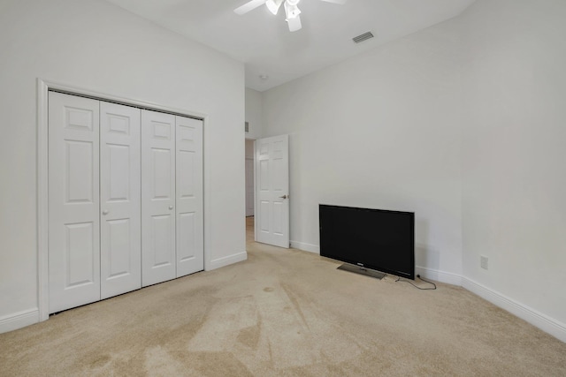 unfurnished bedroom with light carpet, ceiling fan, and a closet