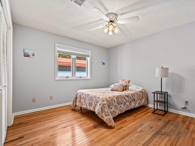 bedroom featuring ceiling fan, light hardwood / wood-style floors, a textured ceiling, and a closet