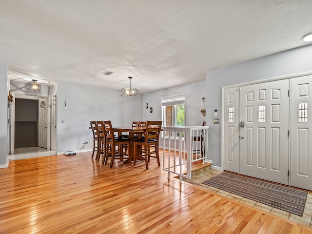 foyer entrance with light hardwood / wood-style floors and an inviting chandelier