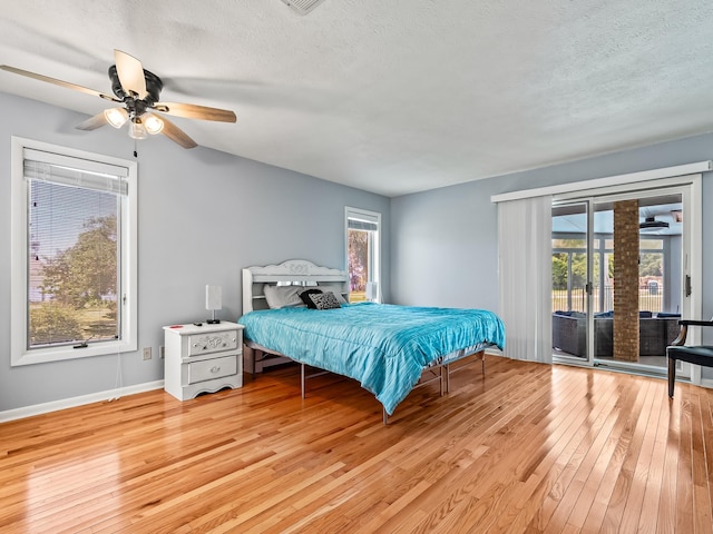 bedroom featuring ceiling fan, light hardwood / wood-style floors, access to exterior, and multiple windows