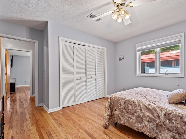 bedroom with a textured ceiling, light wood-type flooring, a closet, and ceiling fan