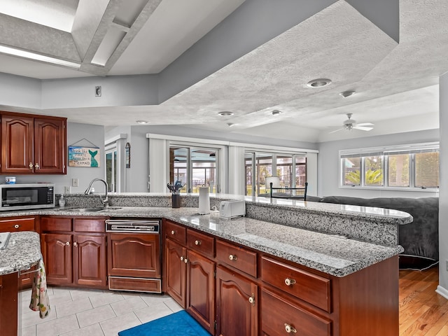 kitchen featuring light stone counters, a textured ceiling, ceiling fan, sink, and dishwasher