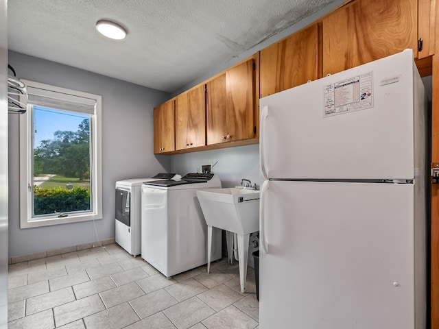 washroom with light tile patterned floors, cabinets, a textured ceiling, and independent washer and dryer