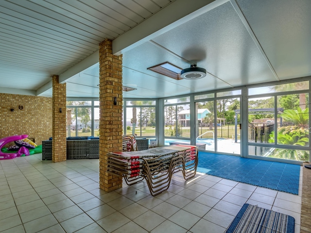 sunroom featuring beam ceiling and a skylight