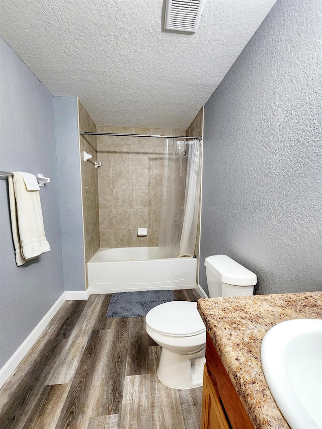 full bathroom with toilet, hardwood / wood-style floors, a textured ceiling, vanity, and shower / bathtub combination with curtain