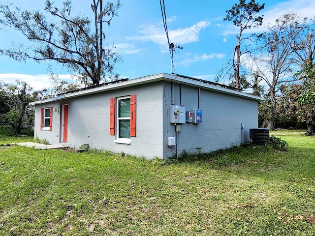 view of side of property featuring central AC unit and a yard