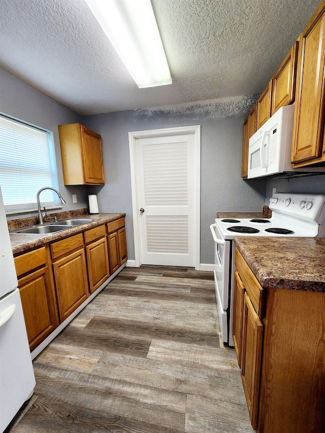 kitchen featuring a textured ceiling, light hardwood / wood-style flooring, sink, and white appliances