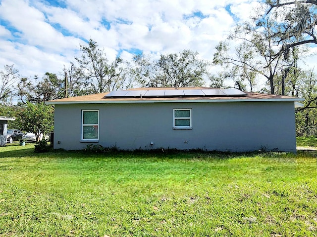 back of house featuring solar panels and a lawn