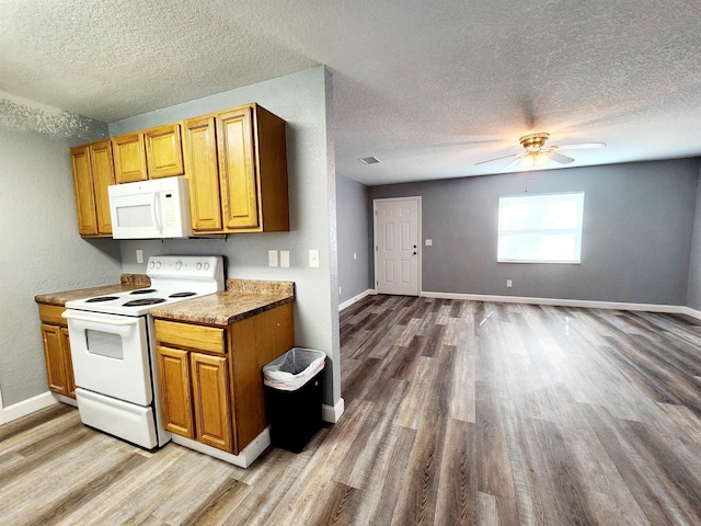 kitchen featuring light wood-type flooring, white appliances, and a textured ceiling