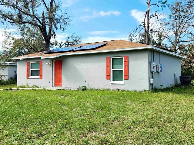 view of front of house featuring central air condition unit, solar panels, and a front yard