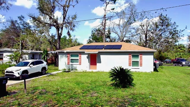 view of front of property with a front yard and solar panels